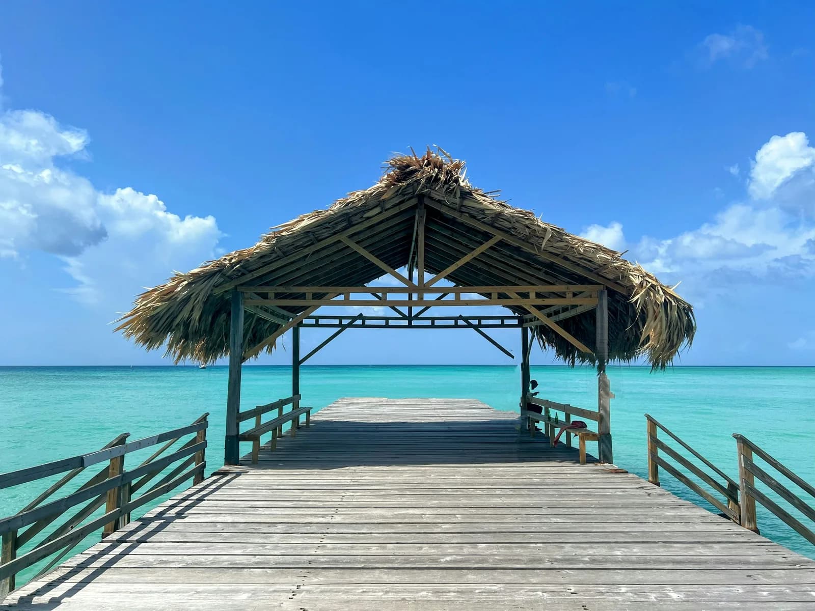 A wooden pier extending over turquoise water in Tobago